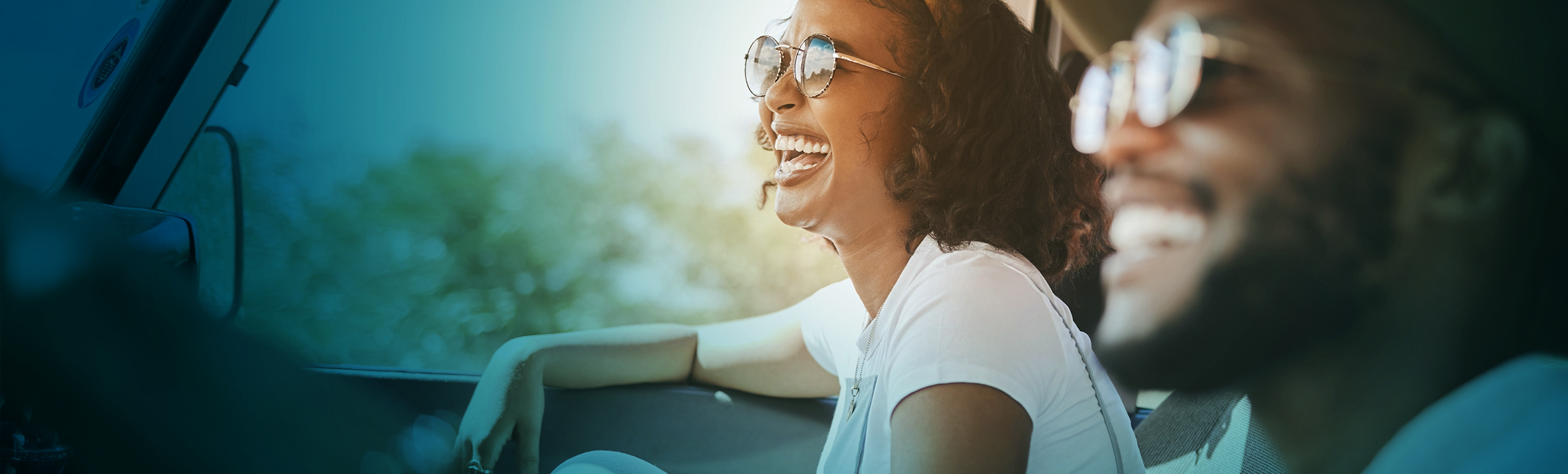 Two adults smiling while riding in a car.